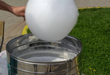 Makine tatlı yün, üretim yapmak için. Tatlı Beyaz Pamuk yün bir park arka plan karşı elinde bir sopa