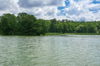 Manzara çevrili ağaçlar ve kıyı ve mavi gökyüzünde bulutlar karşı uzak ufuk sazlık nehir ortasından güzel bir görüntüsü. Yansıma, su, Turizm hedef