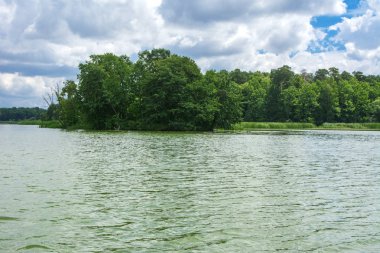 Manzara çevrili ağaçlar ve kıyı ve mavi gökyüzünde bulutlar karşı uzak ufuk sazlık nehir ortasından güzel bir görüntüsü. Yansıma, su, Turizm hedef