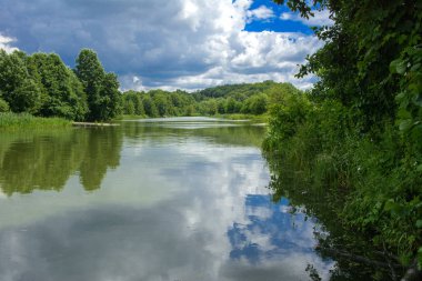 Manzara çevrili ağaçlar ve kıyı ve mavi gökyüzünde bulutlar karşı uzak ufuk sazlık nehir ortasından güzel bir görüntüsü. Yansıma, su, Turizm hedef
