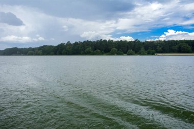 Manzara çevrili ağaçlar ve kıyı ve mavi gökyüzünde bulutlar karşı uzak ufuk sazlık nehir ortasından güzel bir görüntüsü. Yansıma, su, Turizm hedef