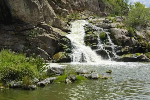 川にある滝の流れと苔と緑と青い空を背景に苔に覆われた岩の上 — ストック写真