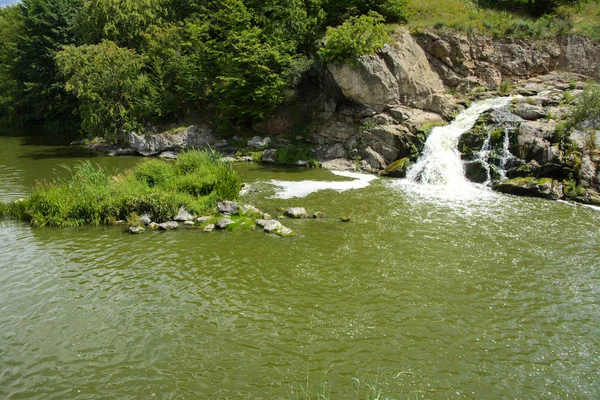 川にある滝の流れと苔と緑と青い空を背景に苔に覆われた岩の上 — ストック写真