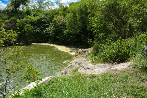 川にある滝の流れと苔と緑と青い空を背景に苔に覆われた岩の上 — ストック写真