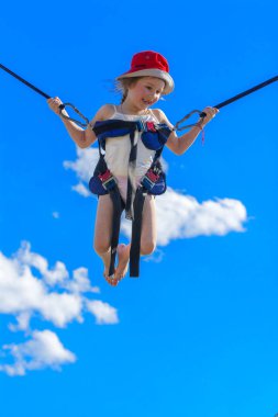 Kauçuk halatlar mavi gökyüzü ile bir trambolin üzerinde atlama çocuk. Macera ve doğa sporları. Yaz eğlence, Zıplama kavramı.