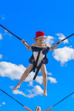 Kauçuk halatlar mavi gökyüzü ile bir trambolin üzerinde atlama çocuk. Macera ve doğa sporları. Yaz eğlence, Zıplama kavramı.