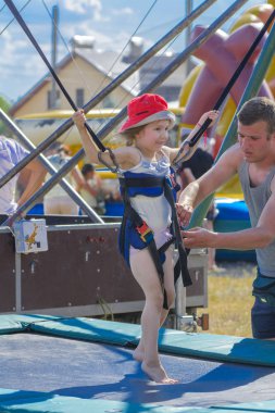 Zarechany, Ukrayna - 10 Haziran 2018. Kauçuk halatlar mavi gökyüzü ile bir trambolin üzerinde atlama çocuk. Macera ve doğa sporları. Yaz eğlence, Zıplama kavramı.