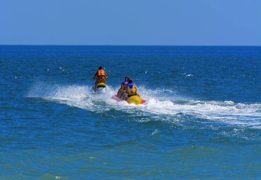 Odessa, Ukrayna - 8 Ağustos 2018. Turistler eğleniyor ve scooter deniz yoluyla taşıma kırmızı ve sarı şişme muz, binme keyfini çıkarın. Yaz tatili, tatil ve seyahat kavramı