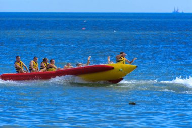 Odessa, Ukrayna - 8 Ağustos 2018. Turistler eğleniyor ve scooter deniz yoluyla taşıma kırmızı ve sarı şişme muz, binme keyfini çıkarın. Yaz tatili, tatil ve seyahat kavramı