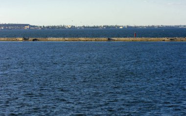 Muhteşem panorama, denizden görünümüne yumuşak güneş ışığı altında gün batımına şehrin kıyı şeridi. Yüksek katlı binalar ve sahilde ticari yapılar