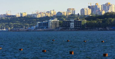 Muhteşem panorama, denizden görünümüne yumuşak güneş ışığı altında gün batımına şehrin kıyı şeridi. Yüksek katlı binalar ve sahilde ticari yapılar