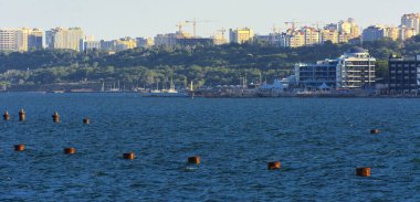 Muhteşem panorama, denizden görünümüne yumuşak güneş ışığı altında gün batımına şehrin kıyı şeridi. Yüksek katlı binalar ve sahilde ticari yapılar