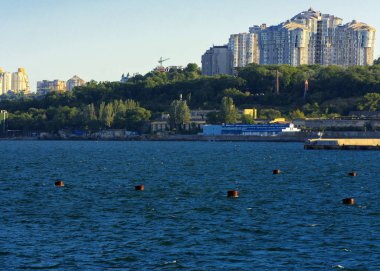 Muhteşem panorama, denizden görünümüne yumuşak güneş ışığı altında gün batımına şehrin kıyı şeridi. Yüksek katlı binalar ve sahilde ticari yapılar