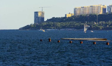 Muhteşem panorama, denizden görünümüne yumuşak güneş ışığı altında gün batımına şehrin kıyı şeridi. Yüksek katlı binalar ve sahilde ticari yapılar