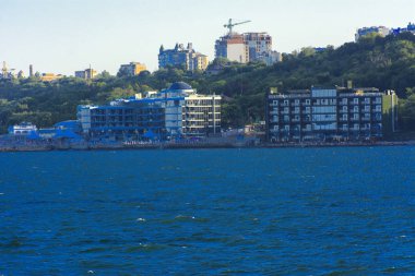 Odessa, Ukrayna - 08 Ağustos 2018. Denizin muhteşem manzara yumuşak bir ışık gün batımından önce şehrin kıyı şeridinde. Yüksek katlı binalar ve sahilde ticari yapılar