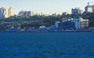 Odessa, Ukrayna - 08 Ağustos 2018. Denizin muhteşem manzara yumuşak bir ışık gün batımından önce şehrin kıyı şeridinde. Yüksek katlı binalar ve sahilde ticari yapılar