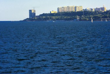 Muhteşem panorama, denizden görünümüne yumuşak güneş ışığı altında gün batımına şehrin kıyı şeridi. Yüksek katlı binalar ve sahilde ticari yapılar