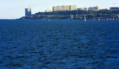 Muhteşem panorama, denizden görünümüne yumuşak güneş ışığı altında gün batımına şehrin kıyı şeridi. Yüksek katlı binalar ve sahilde ticari yapılar