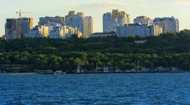 Muhteşem panorama, denizden görünümüne yumuşak güneş ışığı altında gün batımına şehrin kıyı şeridi. Yüksek katlı binalar ve sahilde ticari yapılar