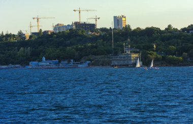Odessa, Ukrayna - 08 Ağustos 2018. Denizin muhteşem manzara yumuşak bir ışık gün batımından önce şehrin kıyı şeridinde. Yüksek katlı binalar ve sahilde ticari yapılar