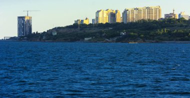 Muhteşem panorama, denizden görünümüne yumuşak güneş ışığı altında gün batımına şehrin kıyı şeridi. Yüksek katlı binalar ve sahilde ticari yapılar