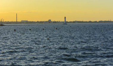 Muhteşem panorama, denizden görünümüne yumuşak güneş ışığı altında gün batımına şehrin kıyı şeridi. Yüksek katlı binalar ve sahilde ticari yapılar
