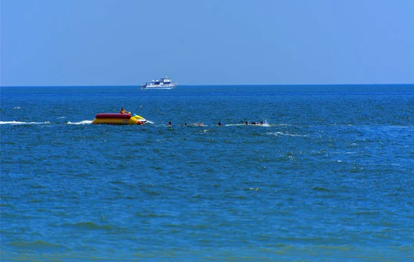 Odessa, Ukrayna - 8 Ağustos 2018. Turistler eğleniyor ve scooter deniz yoluyla taşıma kırmızı ve sarı şişme muz, binme keyfini çıkarın. Yaz tatili, tatil ve seyahat kavramı