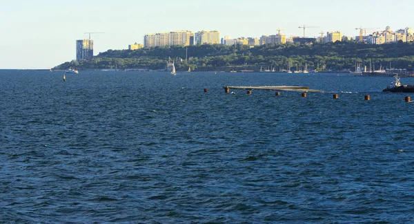 Muhteşem panorama, denizden görünümüne yumuşak güneş ışığı altında gün batımına şehrin kıyı şeridi. Yüksek katlı binalar ve sahilde ticari yapılar