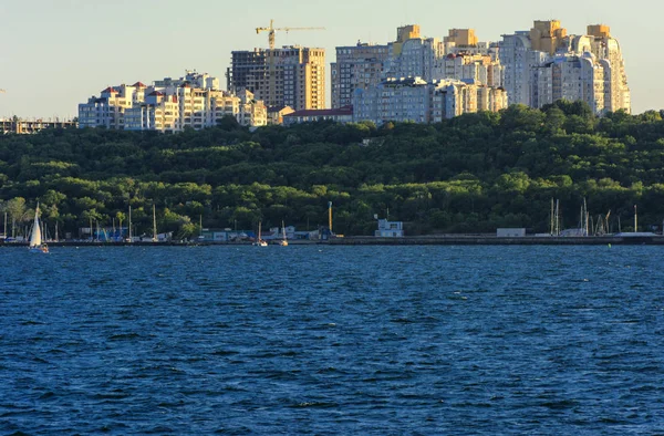 Muhteşem panorama, denizden görünümüne yumuşak güneş ışığı altında gün batımına şehrin kıyı şeridi. Yüksek katlı binalar ve sahilde ticari yapılar