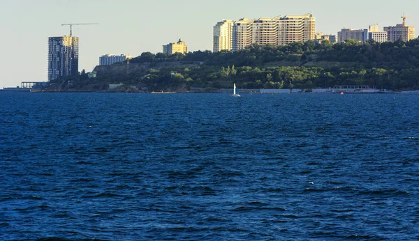 Muhteşem panorama, denizden görünümüne yumuşak güneş ışığı altında gün batımına şehrin kıyı şeridi. Yüksek katlı binalar ve sahilde ticari yapılar