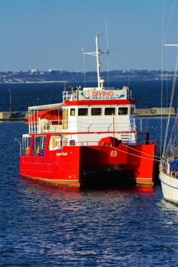 Odessa, Ukrayna - 08 Ağustos 2018. Açık denizde deniz yürüyüşleri için muhteşem bir kırmızı Katamaran akşam yumuşak güneş ışığı altında rıhtımın palamarla. Yaz kavramı, tatil Maceraları.