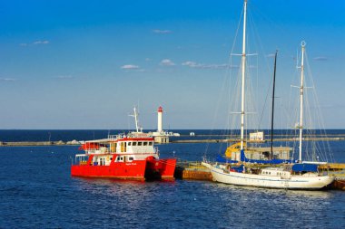 Odessa, Ukrayna - 08 Ağustos 2018. Açık denizde deniz yürüyüşleri için muhteşem bir kırmızı Katamaran akşam yumuşak güneş ışığı altında rıhtımın palamarla. Yaz kavramı, tatil Maceraları.