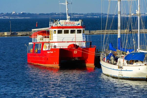 Odessa, Ukrayna - 08 Ağustos 2018. Açık denizde deniz yürüyüşleri için muhteşem bir kırmızı Katamaran akşam yumuşak güneş ışığı altında rıhtımın palamarla. Yaz kavramı, tatil Maceraları.