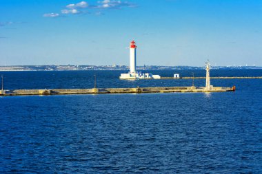 Denizin yumuşak renkler güzel akşam mavi gökyüzünde zemin karşı bağlantı noktasına girişinde bir deniz feneri. Yaz deniz manzarası. Bir kırmızı top ile beyaz deniz feneri. Karadeniz. Odessa Limanı