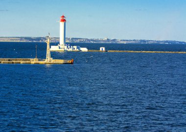 Denizin yumuşak renkler güzel akşam mavi gökyüzünde zemin karşı bağlantı noktasına girişinde bir deniz feneri. Yaz deniz manzarası. Bir kırmızı top ile beyaz deniz feneri. Karadeniz. Odessa Limanı