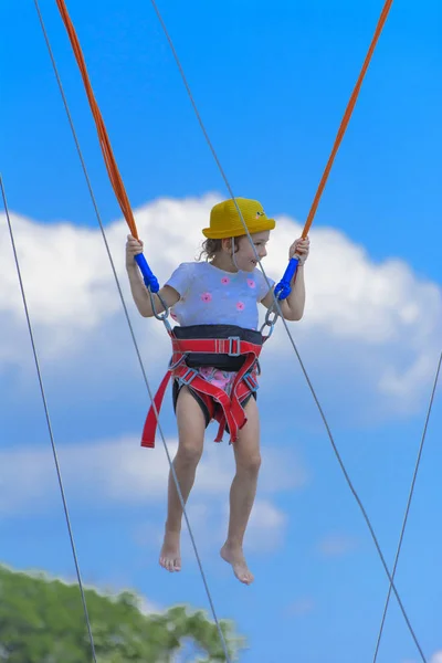 Uma Menina Salta Alto Trampolim Com Cordas Borracha Contra Céu — Fotografia de Stock