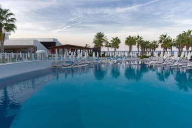 Alanya, Türkiye - 05 Ekim 2018. Kirman Sidera lüks otel ile güzel havuzu temiz deniz, mavi gökyüzü ve yeşil palmiye ağaçları zemin üzerine mavi su. Plaj şezlong, yaz tatili, turizm