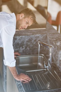Biraz dinlenmeye ihtiyacım var. Profesyonel ciddi adam leanign onun el yıkama sonra masada