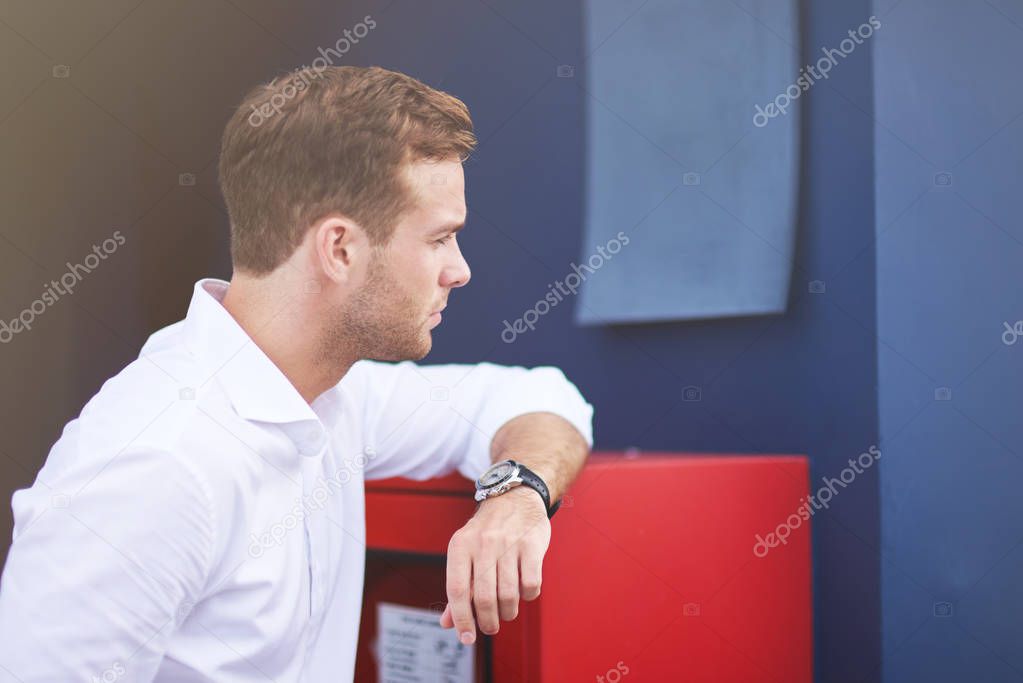 Confident look. Waist up of a serious smart yougn businessman looking aside and being sucessful while standing near the wall