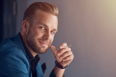 Stresten kurtulmak için en iyi yol. Pozitif yakışıklı işadamı gülümseyen ve bir sigara içilmeyen süre tutarak yakın çekim