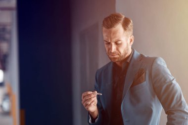Sigarayı. Bir sigara tutan ve kötü alışkanlığı hakkında düşünürken memnun duygu ponponsuz yakışıklı işadamı kadar bel