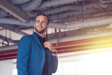 Şık bir görünüm. Kendinden emin bir yakışıklı işadamı kravatını dokunmaktan ve bir kenara bir kentsel çevre içinde duran arıyorsunuz düşük açılı