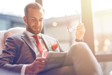 Haberdar. Bir gazete okuyor ve kalkış salonda otururken dinlenme neşeli profesyonel yakışıklı işadamı