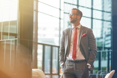 Gerçek lider. Elleri ceplerinde tutan ve bir kenara ofis binası önünde duran süre seyir olumlu emin iş adamı