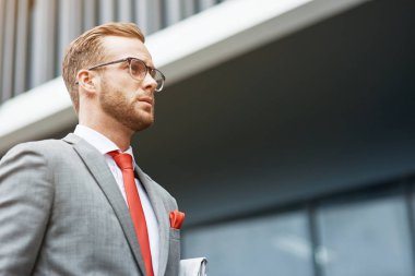 İş kavramı. Bir kenara seyir ve ofis binası yakınında duran profesyonel kendine güvenen genç işadamı