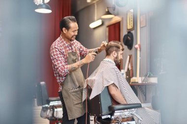 Zevk ile. Neşeli Tay profesyonel kuaför tıraş ve bir tarak bir saç kesimi için onun düzenli istemcisi kullanarak