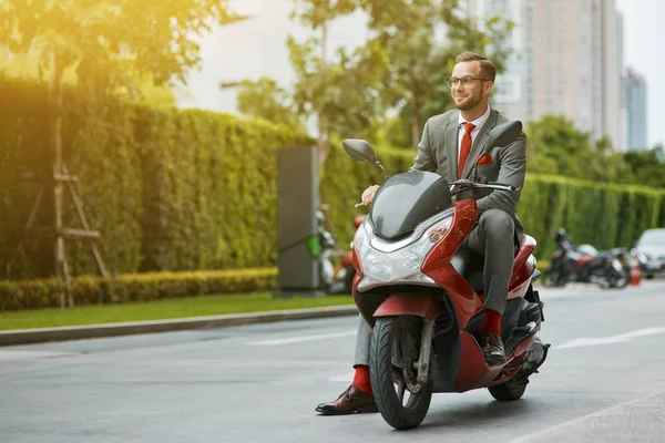 Quickest way to work. Cheerful young handsome businessman sitting on the motorbike and expressing joy while going to have a ride