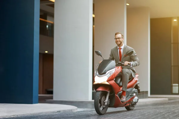 Active way of life. Cheerful young businessman riding a motorbike and expressing gladness while getting to work
