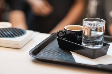 Uygun hizmet. Coffeee ayakta su yakınındaki tepsisindeki bir fincan kapatmak