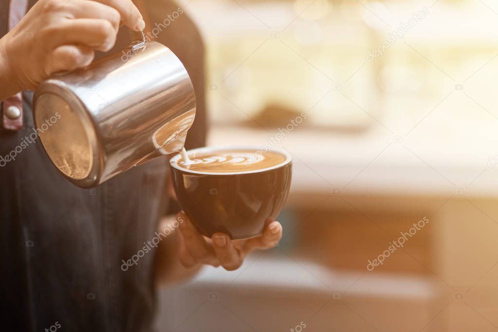 Try it up. Close up of a professional barista holding a cup of coffee and adding milk while working in the coffee shop